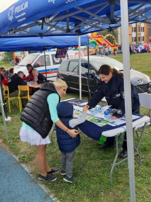 Zdjęcie przedstawiające policjantkę stojącą przy stoisku promującym bezpieczeństwo