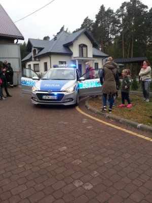 Zdjęcie przedstawiające policjanta prezentującego dzieciom radiowóz policyjny