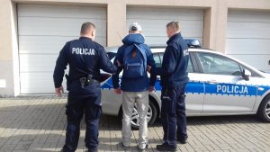 Zdjęcie przedstawiające dwójkę policjantów trzymających osobę zatrzymaną