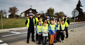 Zdjęcie przedstawiające policjantów stojących wraz dziećmi przy jezdni
