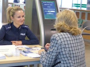 Zdjęcie przedstawiające policjantkę rozmawiającą z kobietą siedzącą przy stole