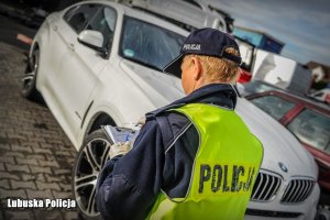 Zdjęcie przedstawiające policjanta na tle odzyskanego BMW