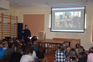 Zdjęcie przedstawiające policjanta podczas prezentacji multimedialnej młodzieży szkolnej