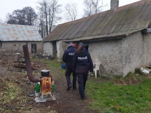 Zdjęcie przedstawiające dwójkę idących po posesji policjantów