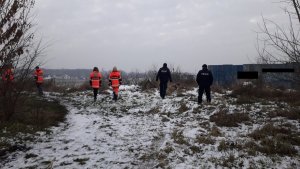 Zdjęcie przedstawiające policjantów wraz z ratownikami medycznymi na otwartym terenie