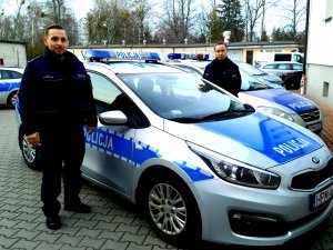 Zdjęcie przedstawiające policjantów stojących koło radiowozu