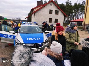 Zdjęcie przedstawiające policjanta prezentującego dzieciom radiowóz