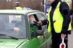 Zdjęcie przedstawiające policjanta stojącego przy aucie