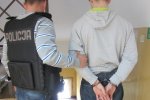 Zdjęcie przedstawiające policjanta wraz z zatrzymanym skutym w kajdanki