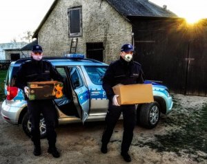 Zdjęcie przedstawiające dwójkę policjantów trzymających kartony z prezentami