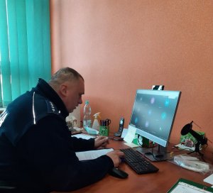 Zdjęcie przedstawiające policjanta  siedzącego przy ekranie monitora