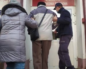 Zdjęcie przedstawiające policjanta pomagającego starszej osobie wejść do przychodni lekarskiej