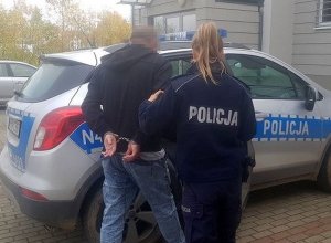 Zdjęcie przedstawiające policjantkę prowadzącą osobę zatrzymaną