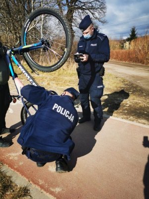 Zdjęcie przedstawiające dwójkę policjantów podczas sprawdzania legalności posiadania roweru