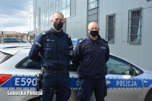 Zdjęcie przedstawiające policjantów stojących przy radiowozie