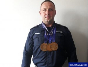 Zdjęcie przedstawiające policjanta ze zdobytymi medalami