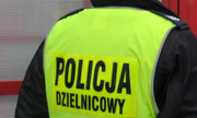 Zdjęcie przedstawiające policjanta ubranego w jaskrawą kamizelkę z napisem Policja