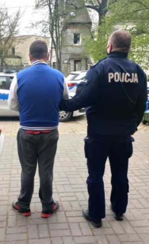 Zdjęcie przedstawiające policjanta stojącego z osoba zatrzymaną
