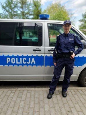 Zdjęcie przedstawiające policjantkę stojącą obok radiowozu