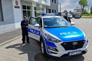 Zdjęcie przedstawiające policjantkę stojąca obok radiowozu