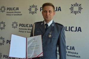 Zdjęcie przedstawiające policjanta z dyplomem