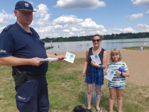 Zdjęcie przedstawiające policjanta stojącego kobietą  i dzieckiem