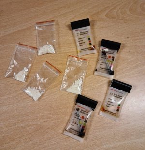 Zdjęcie przedstawiające torebki foliowe typu strunówka z zawartością białego proszku oraz narkotesty