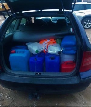 Zdjęcie przedstawiające bagażnik auta z plastikowymi bańkami paliwa