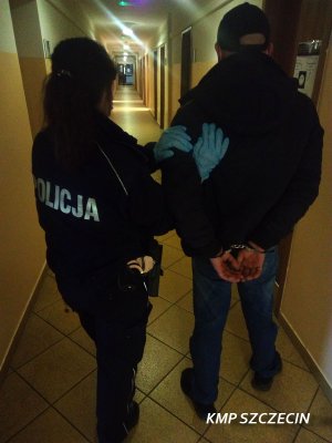 Zdjęcie przedstawiające policjanta stojącego z osobą zatrzymaną