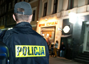 Zdjęcie pleców umundurowanego policjanta na tle ulicy.