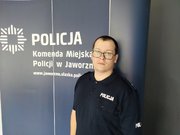 Zdjęcie umundurowanego policjanta na tle ściany z napisem Komenda Miejska Policji w Jaworznie.