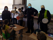 Zdjęcie umundurowanych policjantów w sali lekcyjnej wśród dzieci.