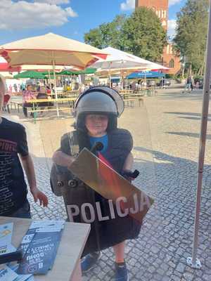 Zdjęcia chłopca z kaskiem na głowie i tarczą z napisem Policja