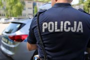 Zdjęcie przedstawiające plecy stojącego na ulicy umundurowanego policjnta