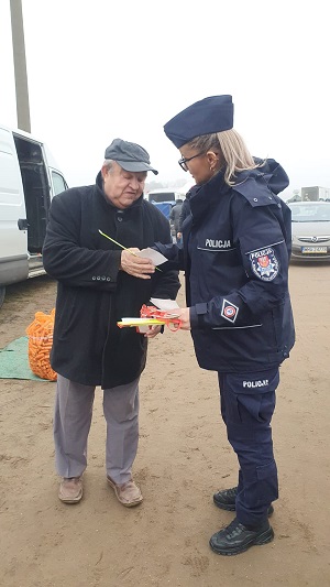 Umundurowana policjantka obo starszego mężczyzny na placu targowym.