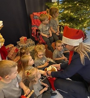 Dzielnicowi ubrani w czapki Mikołaja z wizytą w żłobku