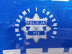 Logo policji z mottem &quot;pomagamy i chronimy&quot; na drzwiach radiowozu.