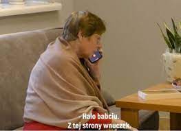Siedząca starsza kobieta trzymająca słuchawkę telefonu przy uchu.