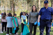 Dzielnicowy z uczniami w lesie podczas sprzątania