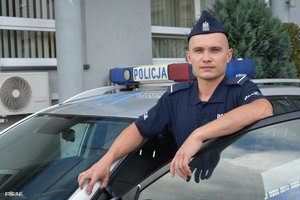 Umundurowany policjant stojący w otwartych drzwiach radiowozu