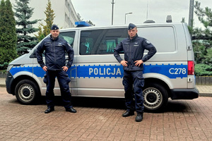 Dwóch policjantów na tle radiowozu typu bus