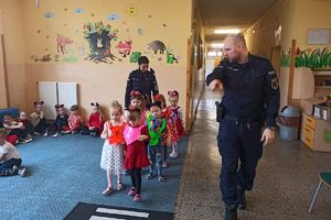 Grupa przedszkolaków, dla których zajęcia prowadzi dwójka policjantów.