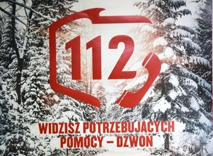 Grafika przedstawiająca scenerię zaśnieżonego lasu z nałożonym czerwonym konturem polski i cyfrą 112