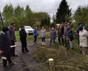 Spotkanie grupy osob z policjantów na tle wejścia na ogrody działkowe