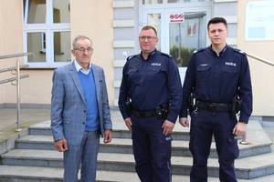 Dwóch policjantów i starszy mężczyzna pozujący do zdjęcia na tle budynku