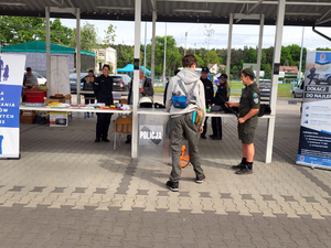 Plenerowe stoisko wystawiennicze Policji, widoczni umundurowani policjanci, harcerze i młodzież