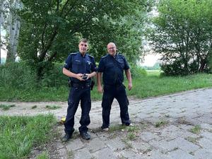 Dwóch umundurowanych policjantów na tle zieleni