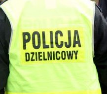 Zbliżenie odblaskowej kamizelki na plecach policjanta - widoczny napis Policja Dzielnicowy