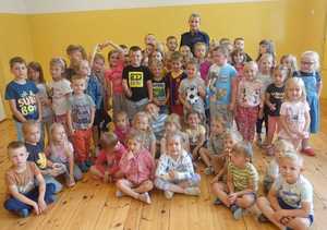 Pozująca do zdjęcia w sali lekcyjnej grupa dzieci z policjantką