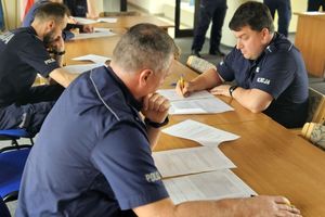 Policjanci przy rozwiązujący testy przy długim stole